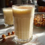 A glass of creamy boza fermented malt drink topped with cinnamon and served with a spoon