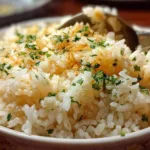 A close-up shot of creamy garlic butter rice garnished with fresh parsley in a white bowl