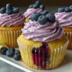 Delicious lemon cupcakes topped with vibrant blueberry buttercream frosting, garnished with fresh blueberries