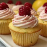 A beautifully decorated lemon raspberry pistachio cupcake topped with fresh raspberries and crushed pistachios on a pastel plate.
