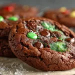 A plate of freshly baked mint brownie cookies topped with chocolate drizzle and mint leaves.