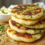 Golden brown traditional Irish potato farls on a wooden board, garnished with fresh herbs